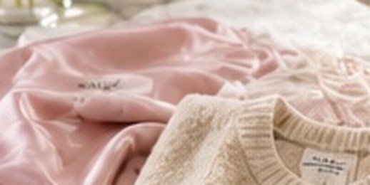 A pink silk garment and a cream cashmere sweater with a care label on a marble counter