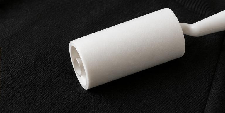 A white lint roller resting on a black knit